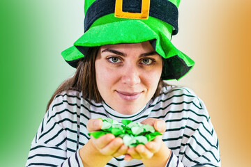 Smiling irish girl in Leprechaun costume holds four leaf clovers.