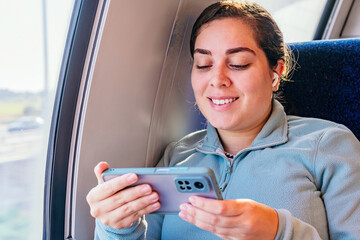 Young woman passenger listening to the music traveling in a train.