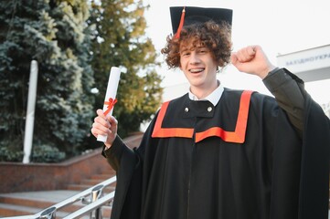 Portrait of a confident and joyful young graduate with a diploma. Man is ready for the next step in...