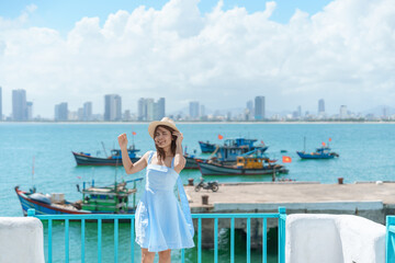 Woman traveler visiting at Son Tra marina. Tourist with blue dress and hat traveling in Da Nang city. Vietnam and Southeast Asia travel concept