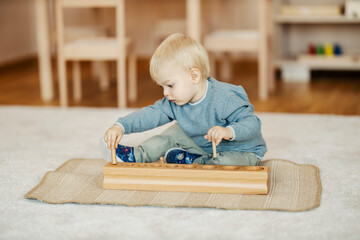 A toddler is is playing with wooden toy, learning shapes at kindergarten.