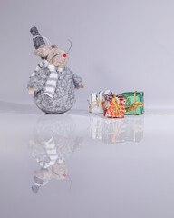 toy Christmas decoration rat on whit background with reflection and presents