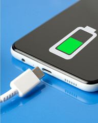 Charging a mobile smartphone on a blue glossy background