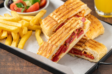 Toast with cheddar cheese and turkish sausage with french fries and salad on wooden table