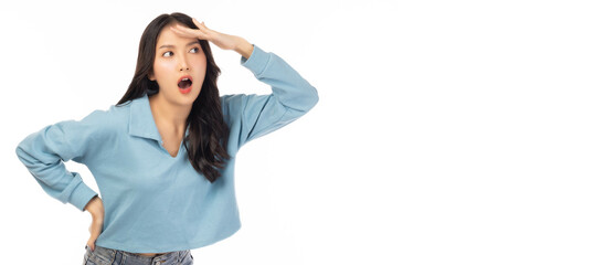 Excited happy young asian woman holding hand above her eyes and looking into copy space looking into distance expecting and searching for something with arm akimbo and smile face use for advertising