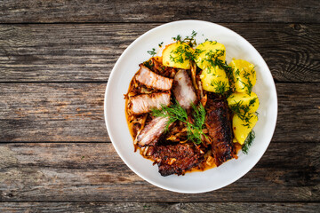 Tasty roast ribs with boiled potatoes on wooden table

