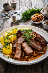 Tasty roast ribs with boiled potatoes on wooden table
