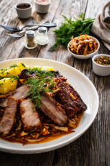 Tasty roast ribs with boiled potatoes on wooden table

