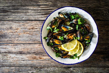 Cooked mussels with lemon and parsley on wooden table
