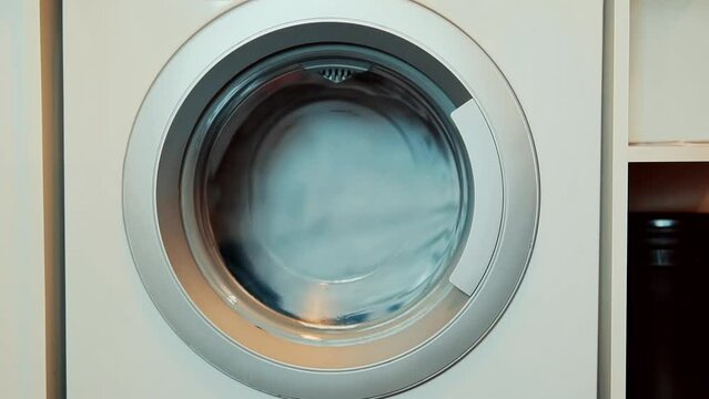 dirty clothes spinning in washing machine drum 