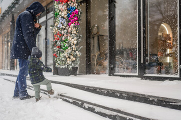 Father and son walking on snow near store