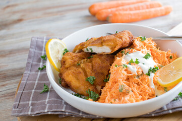 Breaded chicken with carrot salad on a plate. Side view with space for text