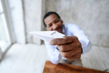 Mature businessman playing with paper airplane in office