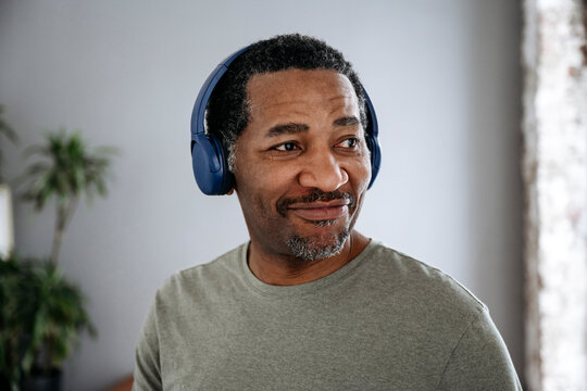 Smiling man listening to music through wireless headphones
