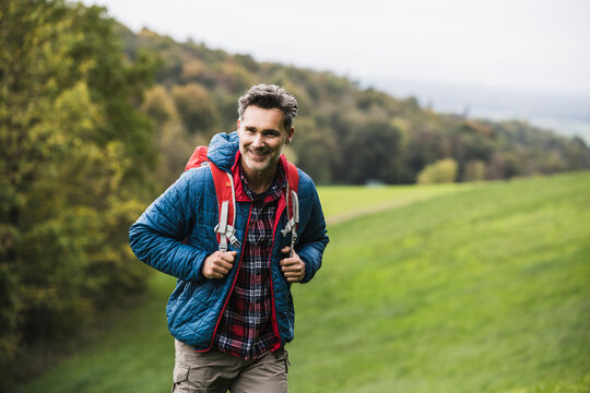 Smiling man with backpack standing on grass