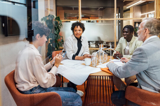 Businesswoman Using Smart Phone With Colleagues In Board Room At Office