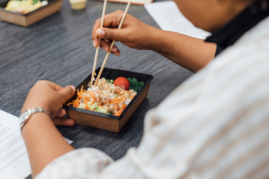 Businesswoman Eating Food At Table In Office