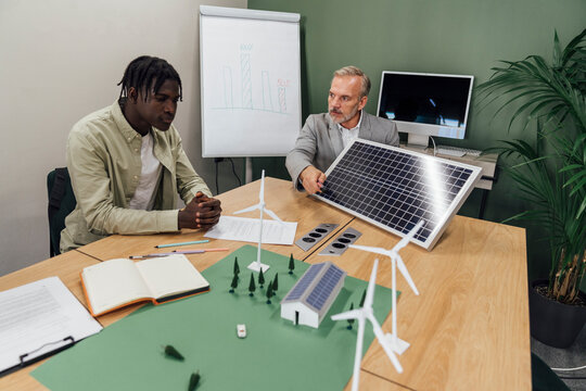 Businessmen discussing on solar panel at table in office