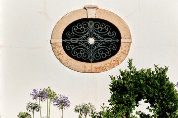 oval window with wrought iron on a facade in Faro, Portugal