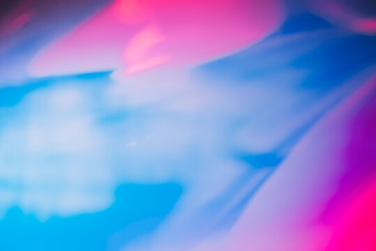 Photo texture of a fashionable holographic film. Abstract colorful holographic futuristic texture. Blurred pink and blue background