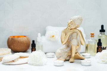 Spa and wellness massage kit with relaxed golden Buddha statue. Concept of Asian relaxing spa procedure with essential oils. Alternative medicine and body care. Selective focus. copy space.