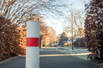 Ein eingefrorener weiß-roter Poller, der die Durchfahrt von Kraftfahrzeugen in der Siedlung...