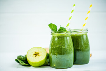 Glasses jars with straws filled with green smoothie and ingredients on wooden table. Vegetarian diet