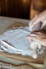 Fototapeta na wymiar Cooking dough for pizza. The cook rolls out the dough and sips the flour