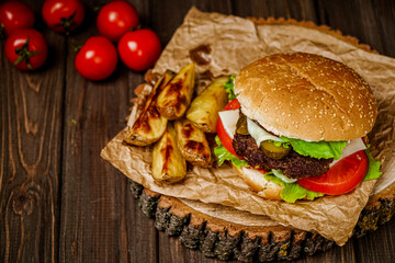From above view hamburger with potato, vegetables on rustic table. Homemade cooking