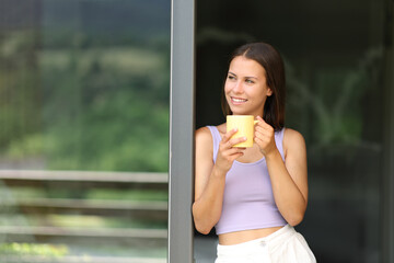 Happy teen drinking coffee leaning in a window - Powered by Adobe