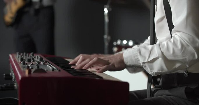 Young pianist is playing a fast paced melody on a keyboard, man playing guitar