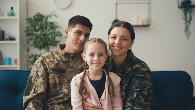 Portrait of cute military family with daughter sitting on sofa, happy childhood - Powered by Adobe