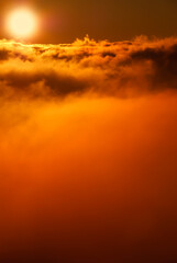 Beautiful sunset / sunrise cloudy sky from aerial view with gentle colorful clouds and dramatic light. Airplane view above clouds. Vivid twilight sky painted by the sun leaving bright golden shades