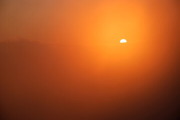 Beautiful sunset / sunrise cloudy sky from aerial view with gentle colorful clouds and dramatic light. Airplane view above clouds. Vivid twilight sky painted by the sun leaving bright golden shades