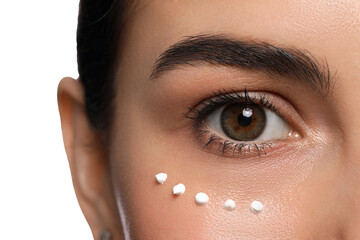 Closeup view of young woman with cream on skin under eye against white background