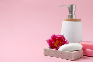 Soap bar and bottle dispenser on pink background, space for text