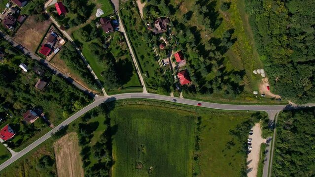 Mountain village and road with moving cars, aerial view. Beautiful mountain landscape with residential neighborhood and green fields. Countryside view