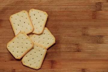 Heap of Dry thin crispy crackers on cutting board on wood table. Top view with copy space