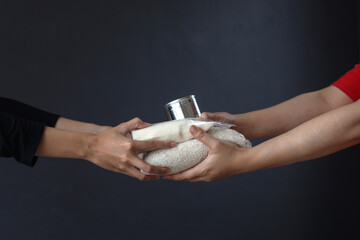 Hands giving and receiving staple food for donation and charity on dark gray background. - obrazy, fototapety, plakaty