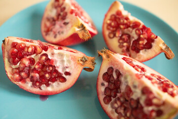 Halves of a pomegranate on a plate, on a light background. Weight loss, proper nutrition, diet, expensive fruits, pomegranate slices. Fruit cutting. cleansing