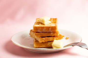 Front view of a pile of belgian waffles with white chocolate on a pink background
