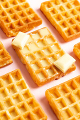 Diagonal vertical view of belgian waffles with white chocolate on a pink background