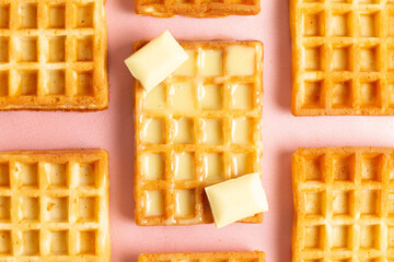 Top view of belgian waffles with white chocolate on a pink background
