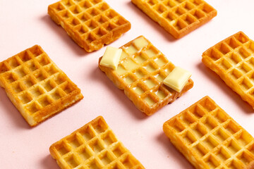 Diagonal view of belgian waffles with white chocolate on a pink background