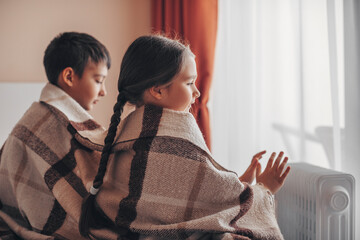 Shutdown of heating and electricity, blackout. Children warm their hands from a battery powered by...