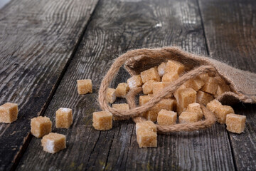 Many pieces of brown sugar on a wooden background. Heap of brown sugar cubes on  wooden table, closeup