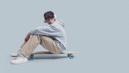 Tuinposter Teenager posing with a skateboard © stokkete