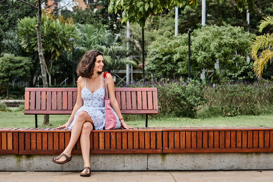 Smiling woman resting on bench in park