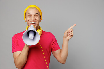 Young man of African American ethnicity wear pink t-shirt yellow hat headphones hold scream in...