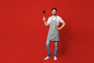 Full body confident young male housewife housekeeper chef cook baker man wear grey apron hold in...
